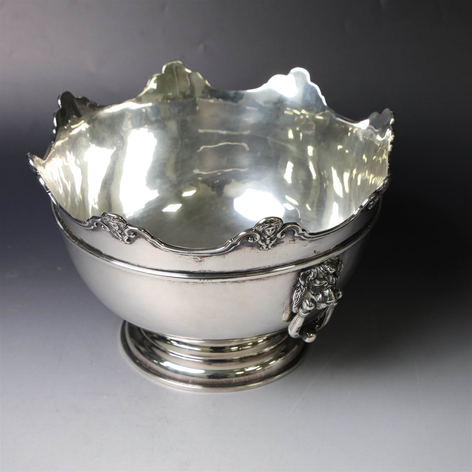 Edwardian silver Monteith punch bowl, the scalloped rim with strapwork and figural decoration, with two lion mask mounted ring handles, upon a circular stepped foot, hallmarked London 1903, maker's mark worn and indistinct, H15cm, D23cm