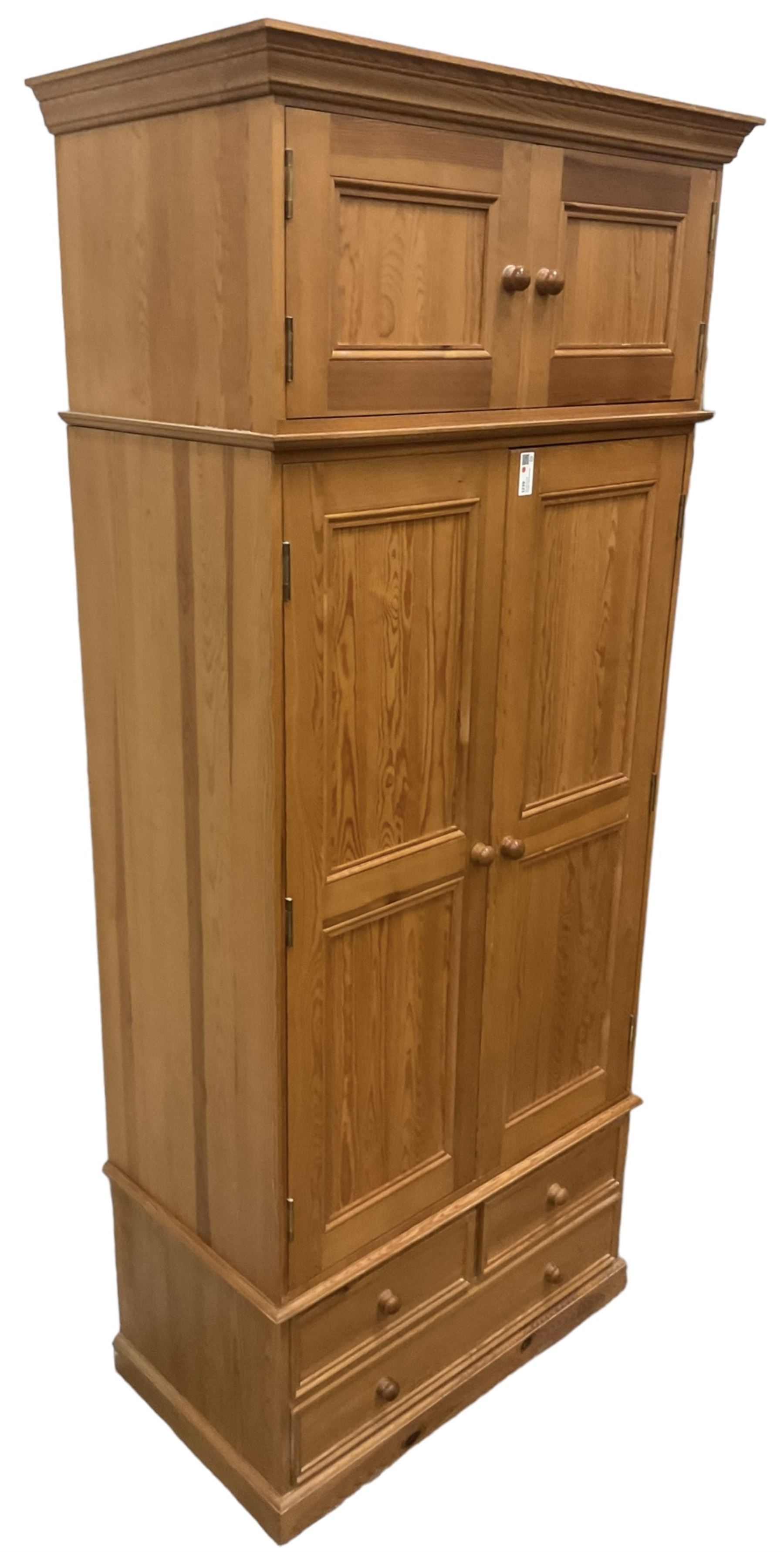 Solid pine double wardrobe, fitted with top box, enclosed by panelled doors, two short and one long drawer, on plinth base 