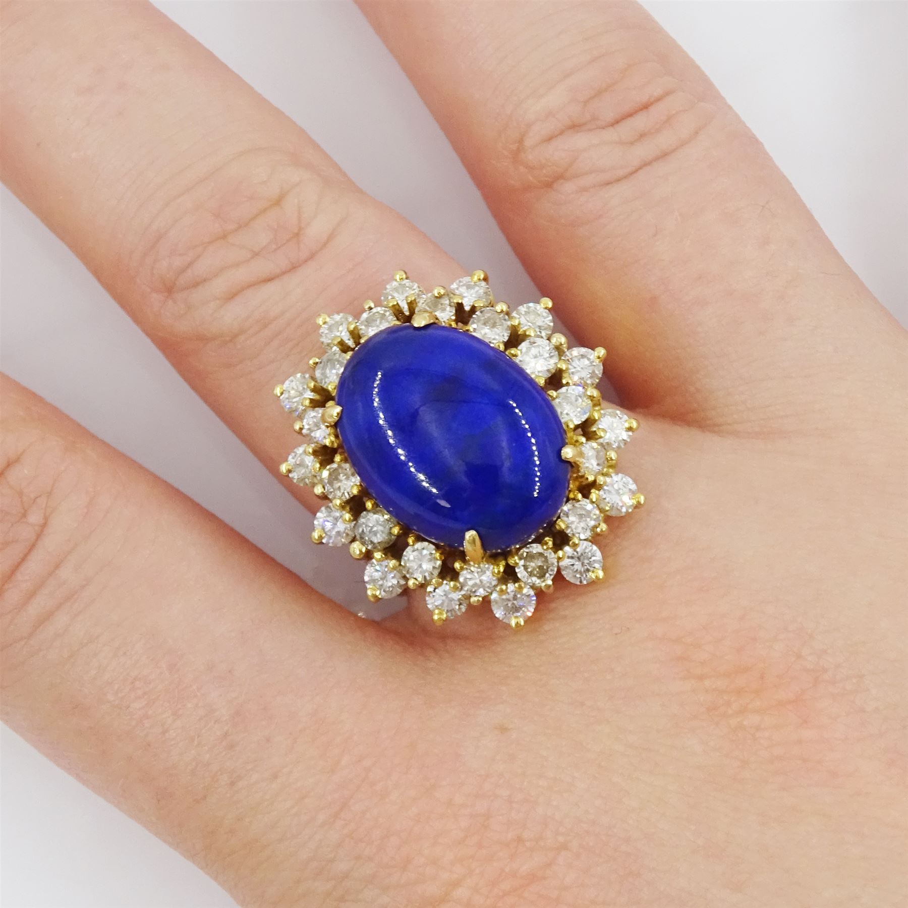 18ct gold lapis lazuli and diamond cluster ring, single oval cut lapis lazuli with two rows of round brilliant cut diamonds, stamped 750, total diamond weight approx 1.70 carat