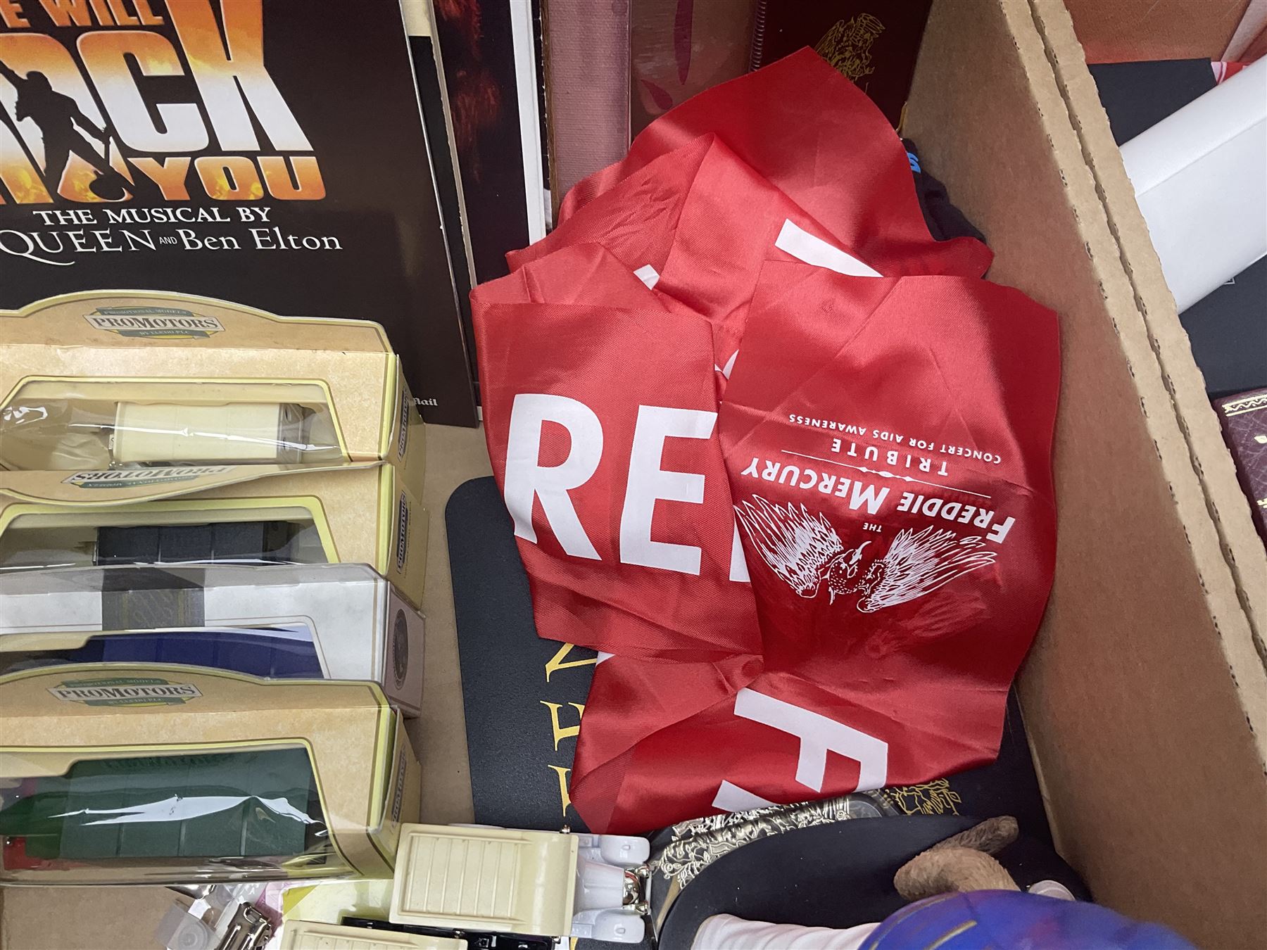 Mostly Queen and Freddie Mercury interest items, including pin badges, newspaper cuttings, diecast 'promotional' vehicles, special edition Pop Rocks figure of Freddie Mercury, VHS tapes, two charity certificates signed by Brian May and Roger Taylor, poster etc, in two boxes 