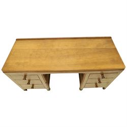 Mouseman - adzed oak kneehole dressing table or desk, the rectangular adzed top with raised back and canted corners, over an arched recessed kneehole flanked by three graduating drawers to each side with turned knob handles, raised on octagonal feet, with carved mouse signature, by the workshop of Robert Thompson of Kilburn