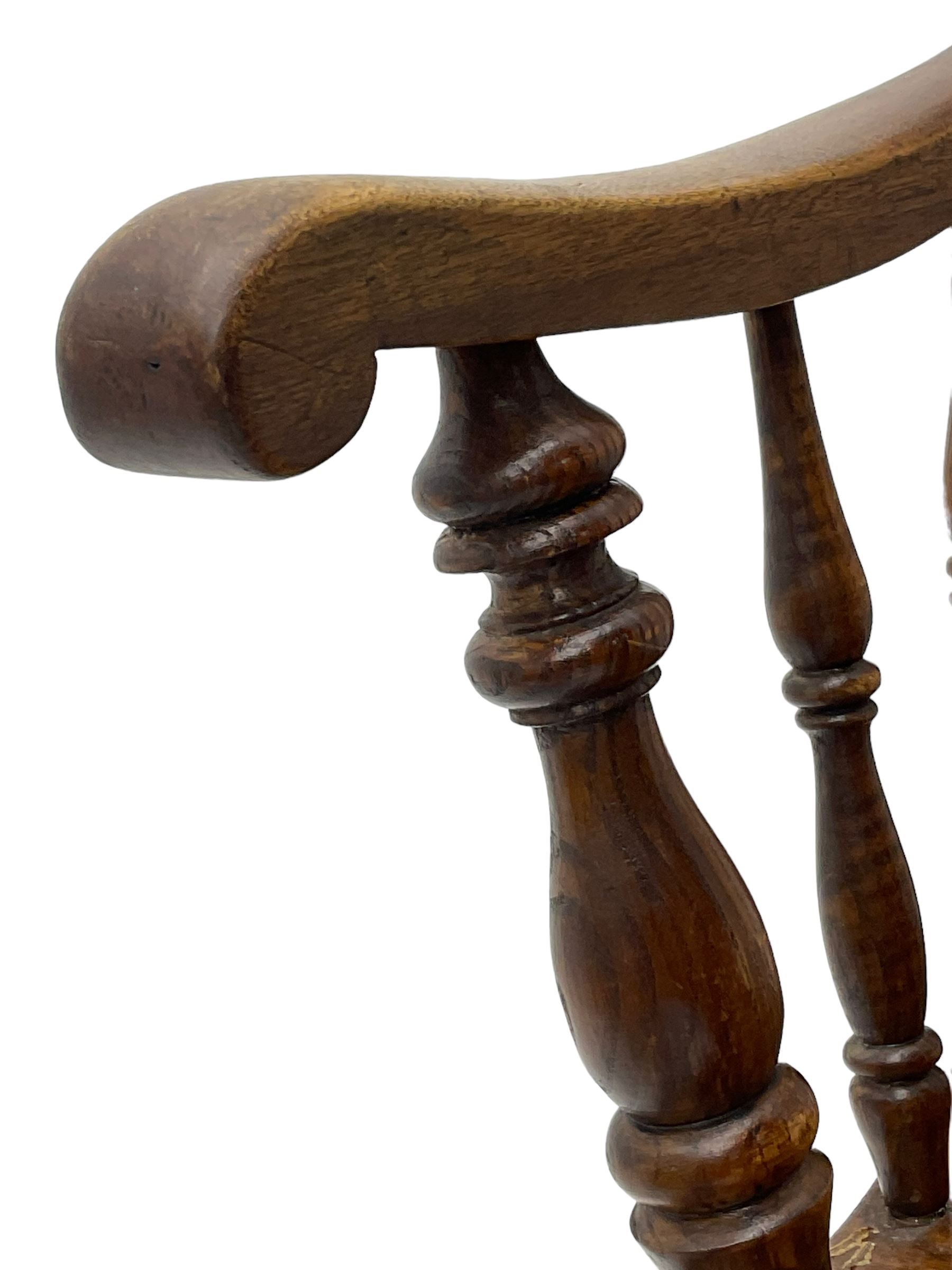 Early 19th century elm farmhouse armchair, the shaped eared cresting rail over tall spindle back, dished seat on turned supports united by H stretchers