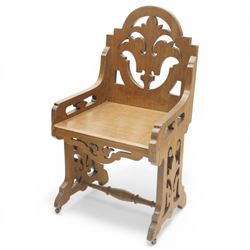 Gothic Revival oak ecclesiastical chairs, shaped cresting rails over pierced foliate splat backs, plank seats above shaped and pierced friezes, raised on shaped end supports united by turned stretchers, on small brass castors
