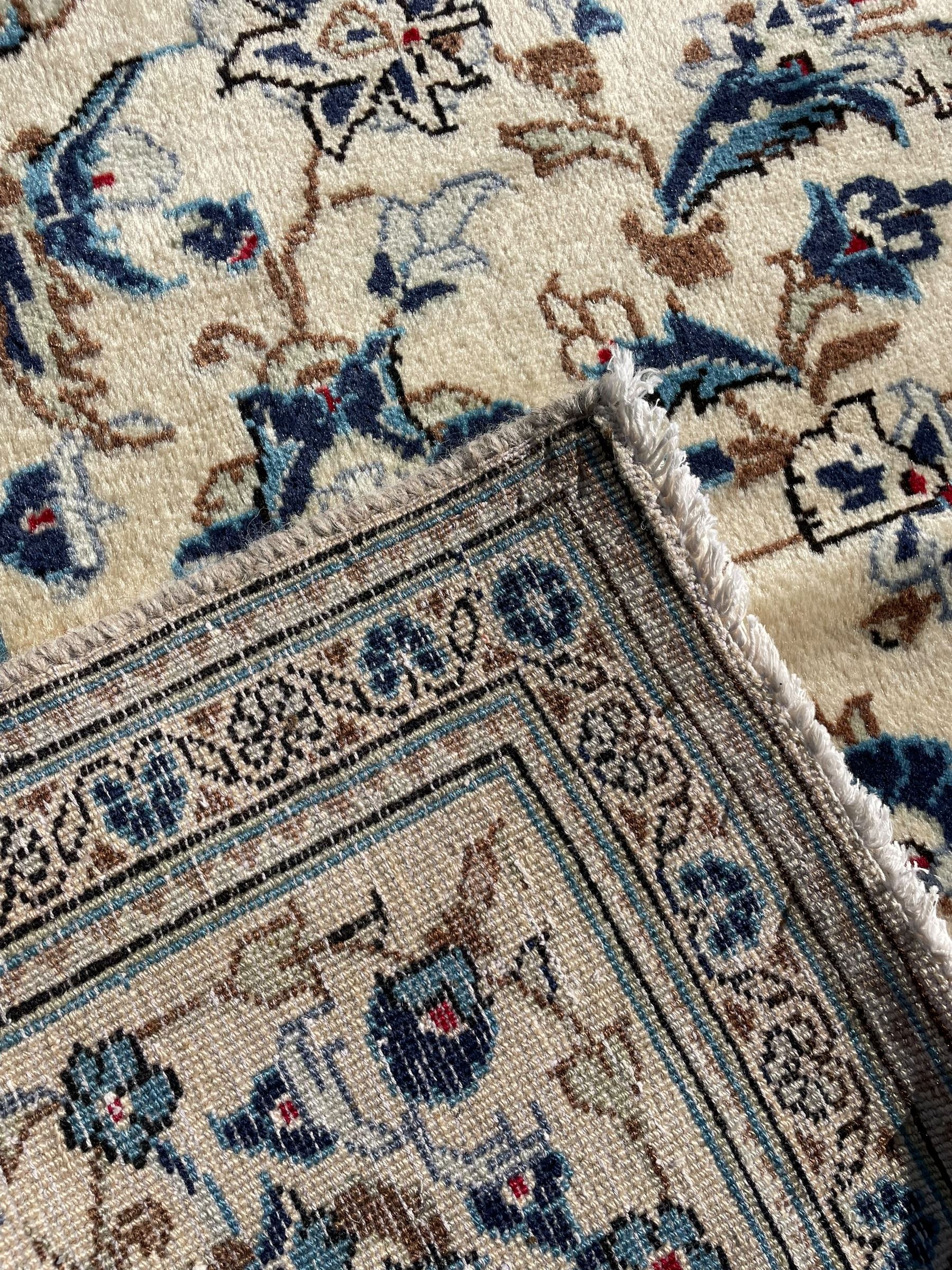 Persian Kashan ivory ground rug, the field decorated with trailing branches with leaves and palmettes, similar scrolling border, within floral pattern guard stripes 