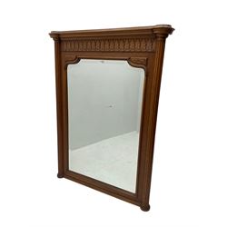 Early 20th century French oak overmantle mirror, projecting cornice with broken foliate carved frieze, shaped rectangular bevelled plate flanked by fluted column uprights