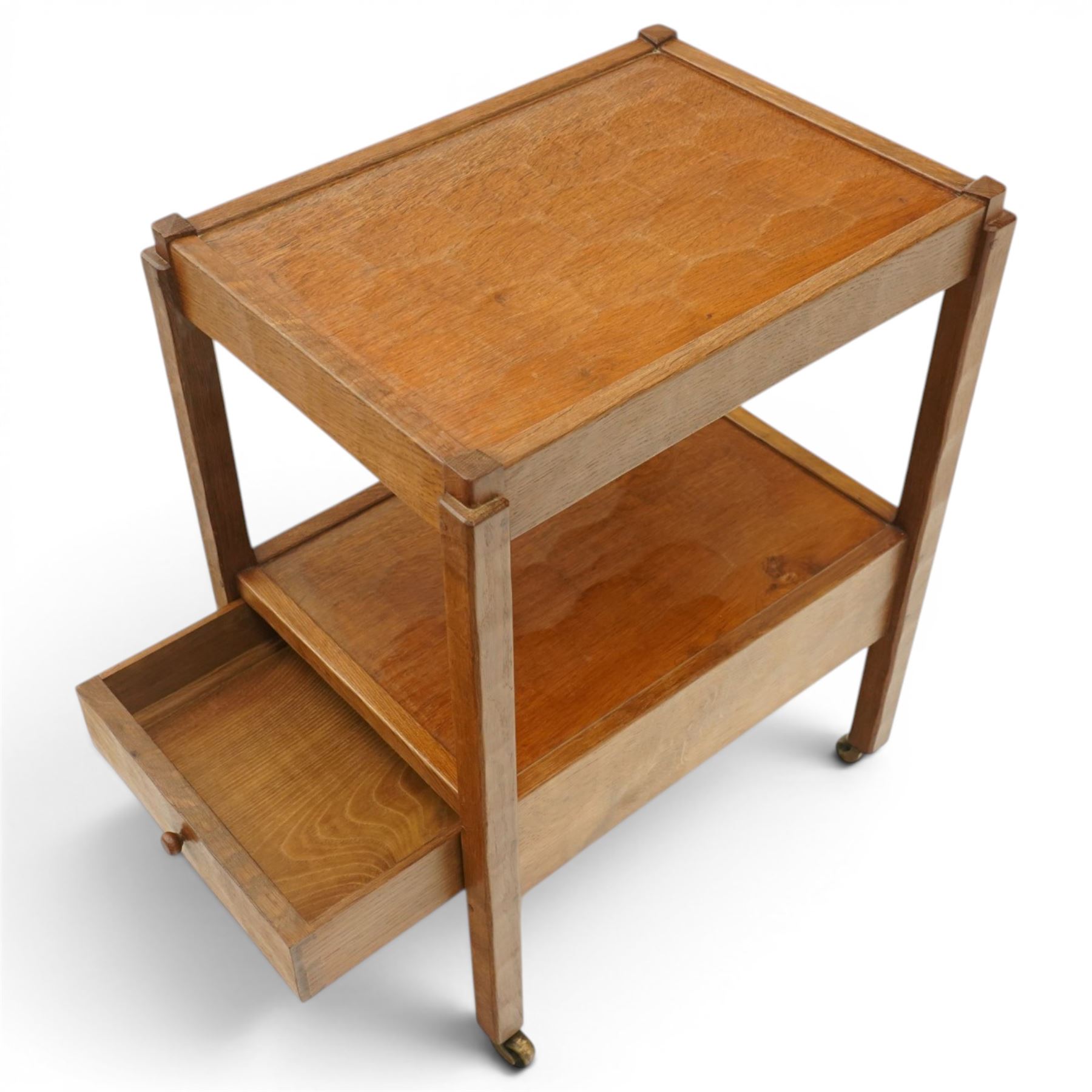 Acornman - oak two tier tea trolley, rectangular adzed top and lower section, with drawer raised on square supports terminating in castors, with carved acorn signature, by the workshop of Alan Grainger of Brandsby