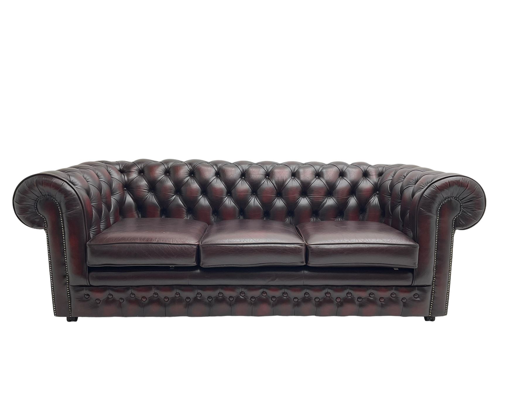 Thomas Lloyd - three seat Chesterfield sofa, upholstered in buttoned oxblood leather, on castors 
