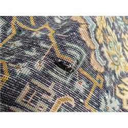 Persian indigo and pale gold ground rug, overall busy geometric design, the field decorated with hooked Hac and palmette medallions surrounded by densely patterned zig-zags and stylised foliate motifs, the border decorated with smaller Hac motifs, within multiple guard stripes 