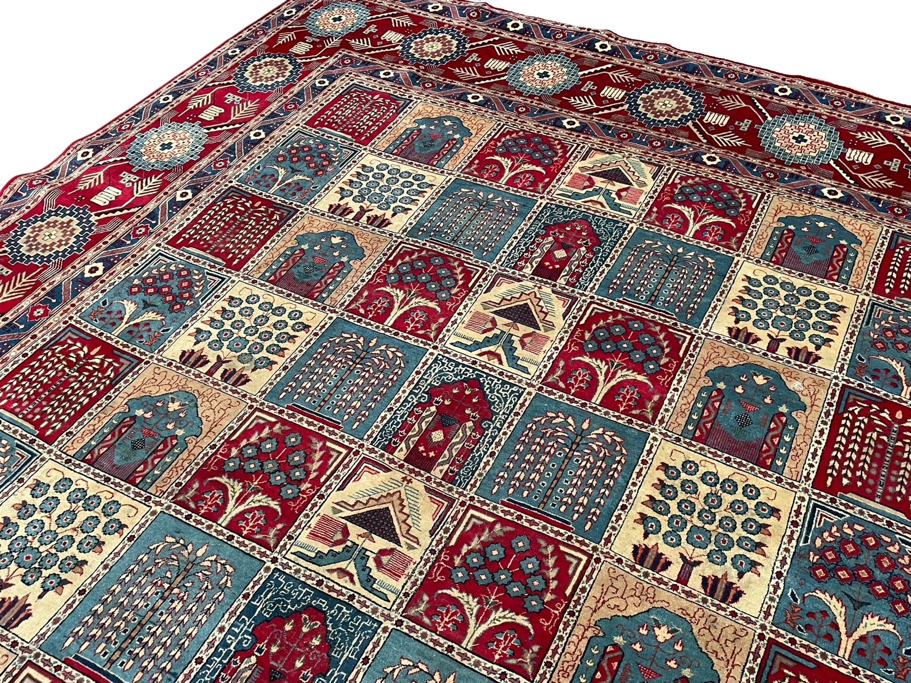 Persian Bakhtiari crimson ground carpet, the field divided into seventy panels decorated tree of life motifs, mihrabs and stylised plants, the border decorated with repeating circular medallions formed of Hac motifs, floral pattern guard stripes 