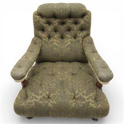 Late Victorian open armchair, in the manner of Howard & Sons, with deep buttoned seat and back upholstered in green damask fabric, with fringed detail to the lower arms, raised upon turned front legs with brass castors