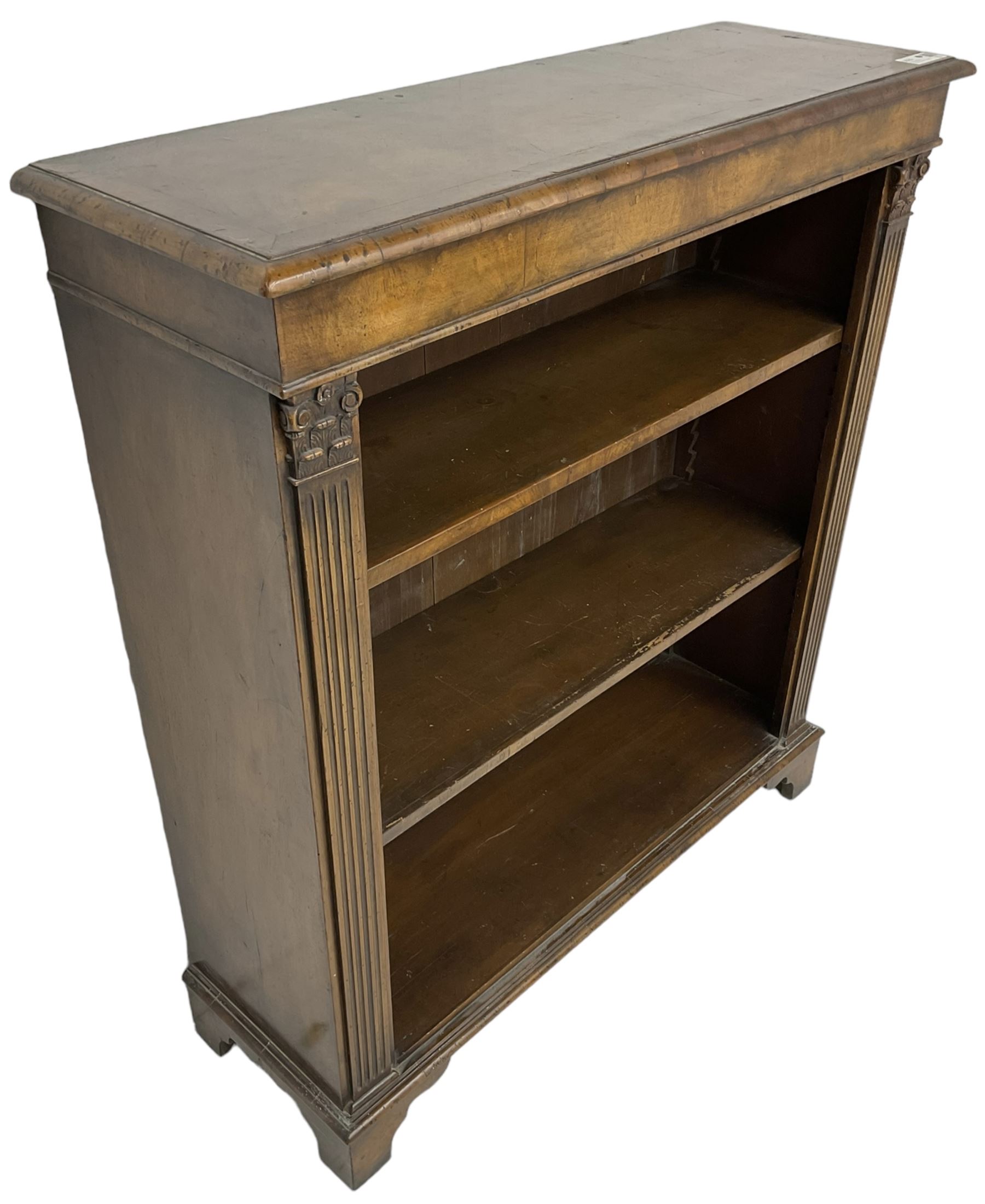 Georgian design walnut open bookcase, fluted uprights with acanthus carved capitals enclosing two adjustable shelves, on bracket feet