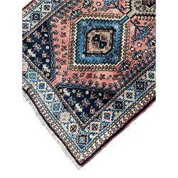 Persian Yalameh coral ground runner rug, the field decorated with seven hooked lozenge medallions surrounded by stylised plant motifs, the indigo spandrels decorated with similar patterns, guarded border with repeating diamond lozenges