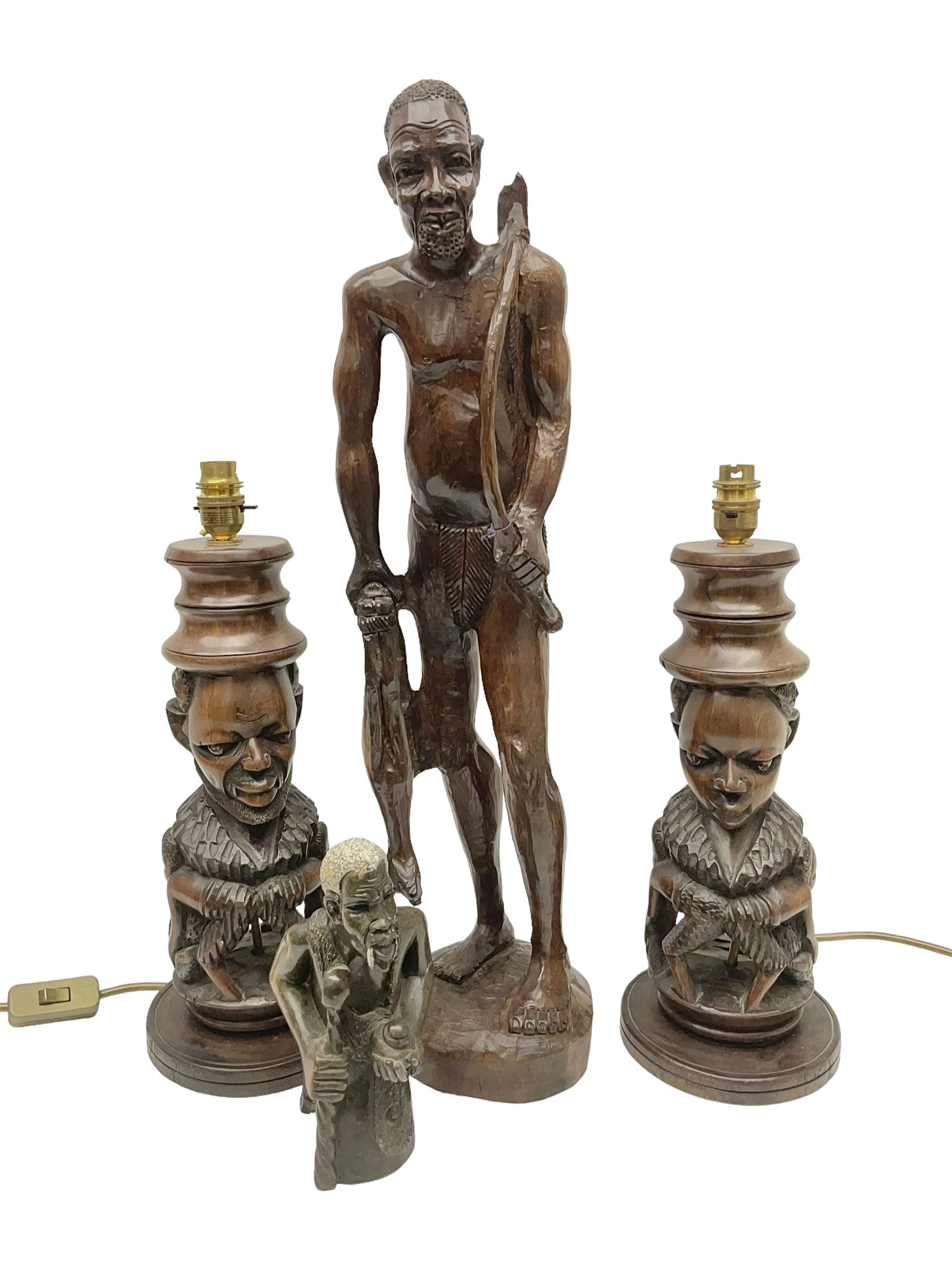 Pair of 20th century carved wood table lamp with African busts and figures, together with a carved wooden figure and soapstone figure, lamps H44cm