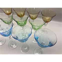 Ten coloured Adriana wine glasses by Abigails, to include blue, green, pink and yellow examples, each with part faceted bowl and twist stems, together with two similar orange examples with pulled stems, H24cm