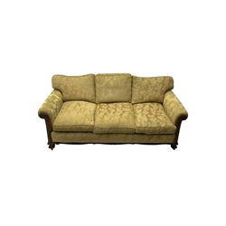 Early 20th century mahogany framed three-piece lounge suite - three-seat camelback sofa (W203cm, D105cm); pair of matching armchairs (W95cm, D96cm); upholstered in neutral foliate pattern fabric, carved with trailing leafy branches, ball and claw carved feet with brass castors 