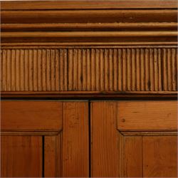 Victorian stripped pine kitchen cupboard, of rectangular form with fluted cornice and top section with two panelled cupboard doors revealing painted shelved interior, middle with two drawers with turned knob handles and brass cup handles, base section with two panelled cupboards, raised on shaped bracket feet 