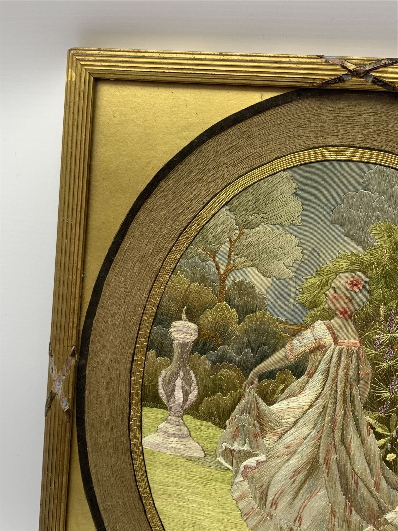 George III silkwork picture, of oval form depicting a female figure in garden setting, within a silkwork border detailed with verse from Robert Burns Bonnie Peg, 'Her air sae sweet, and shape complete, The Queen of Love did never move, Wi' Motion mair enchanting!', and monograms 'FV' and 'SM', in reeded gilt frame and gilt mount, indistinctly inscribed in pencil verso, overall H36cm L30.5cm