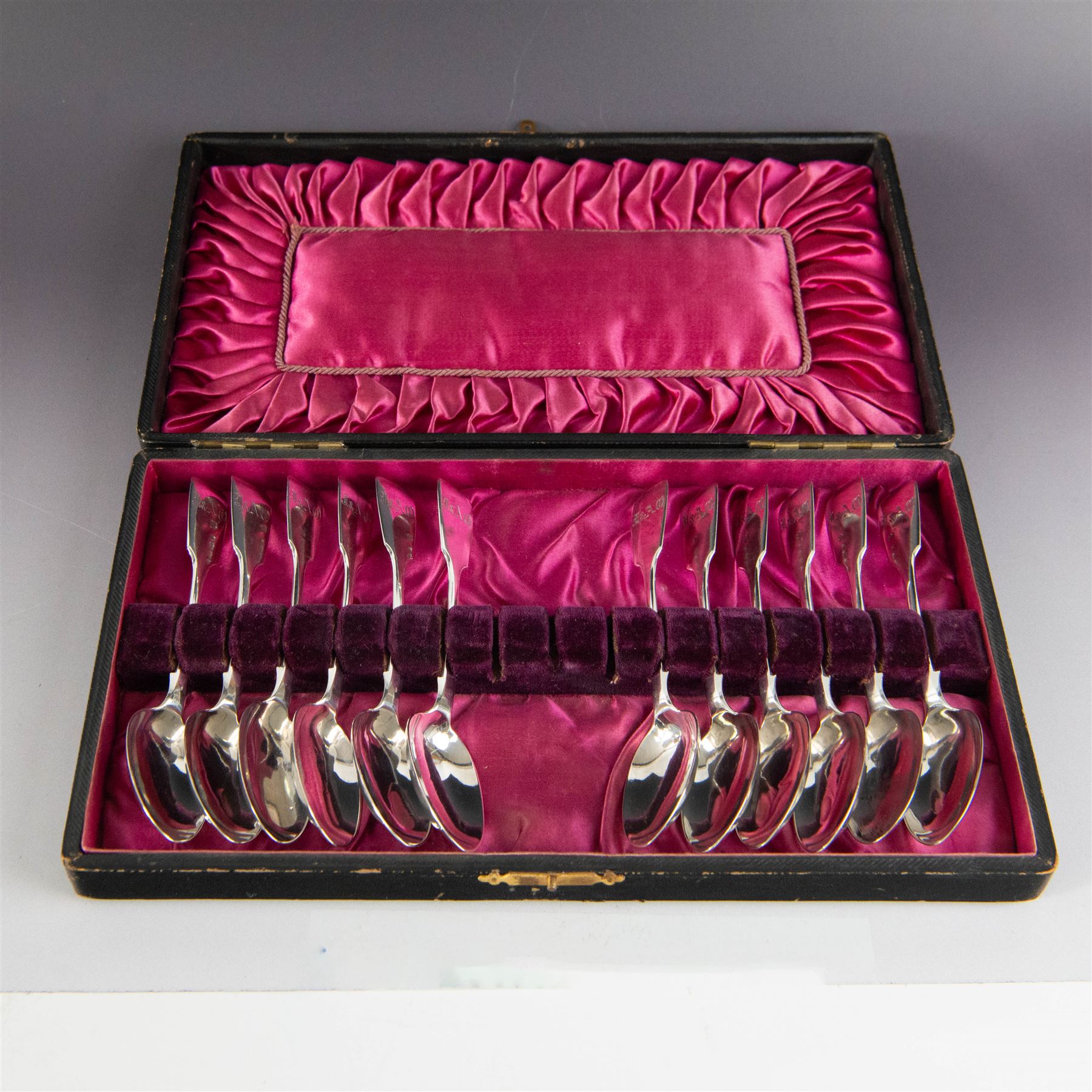 Set of twelve Victorian Exeter silver Fiddle pattern teaspoons, all with engraved initials to terminal, hallmarked Josiah Williams & Co, Exeter 1860, contained within tooled leather case with burgundy silk and velvet lined interior