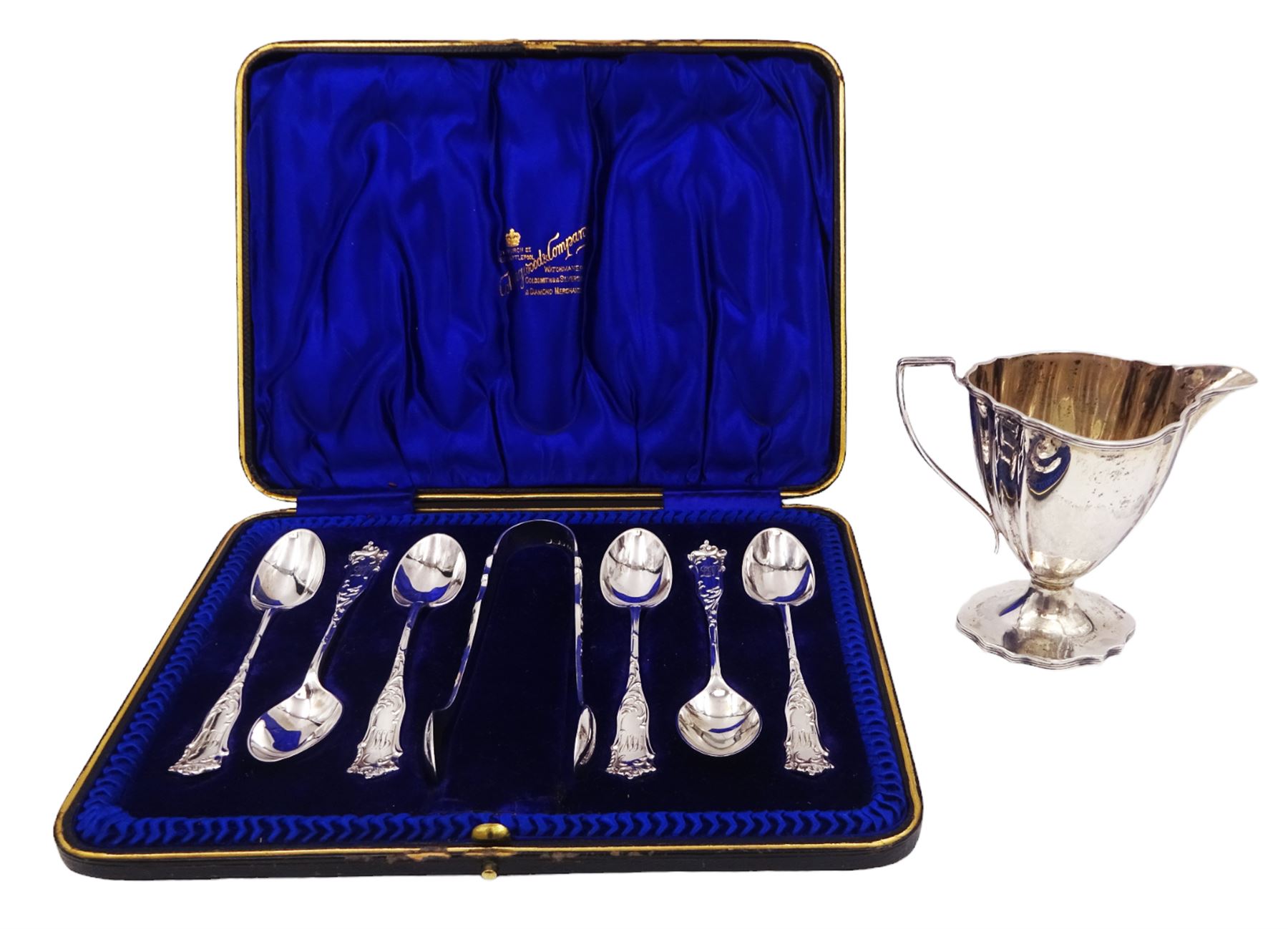 Edwardian silver cream jug, of fluted helmet form, with angular handle and upon shaped foot, hallmarked Birmingham 1905, maker's mark indistinct, together with a set of six Edwardian silver teaspoons and a pair of sugar tongs, all with scrolling embossed decoration and engraved monogram, hallmarked Joseph Rodgers & Sons, Sheffield 1903, within tooled leather fitted case, jug including handle H9cm 