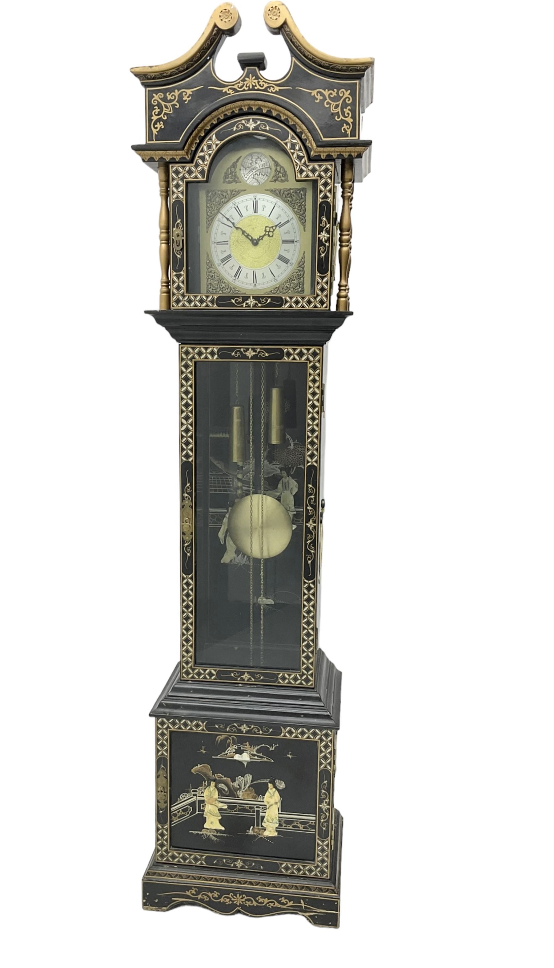 20th century 8-day chain driven black lacquered longcase clock - with a swans neck pediment and break-arch hood door, fully glazed trunk door displaying brass cased weights and pendulum, case sides, hood and plinth profusely decorated in gold relief and chinoiserie figures, brass break arch dial with an etched centre and silvered chapter ring, German two train movement striking the hours and half hours on two gong rods. With weights and pendulum.
