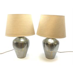 A pair of brushed steel table lamps, of baluster form with gold coloured solder effect decoration, and beige fabric shades, overall H52.5cm.