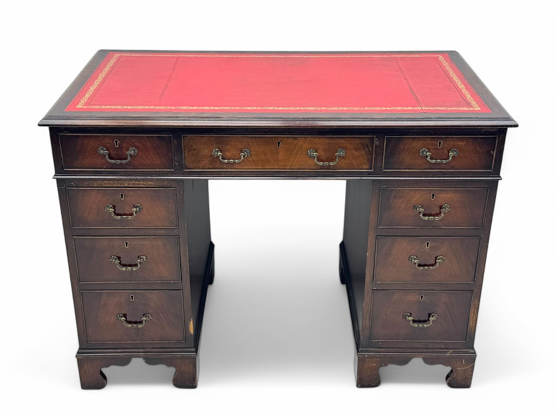 Georgian design mahogany kneehole desk, moulded rectangular top with red gilt-tooled leather writing surface, over an arrangement of nine cock-beaded drawers with brass swan neck handles, on bracket feet