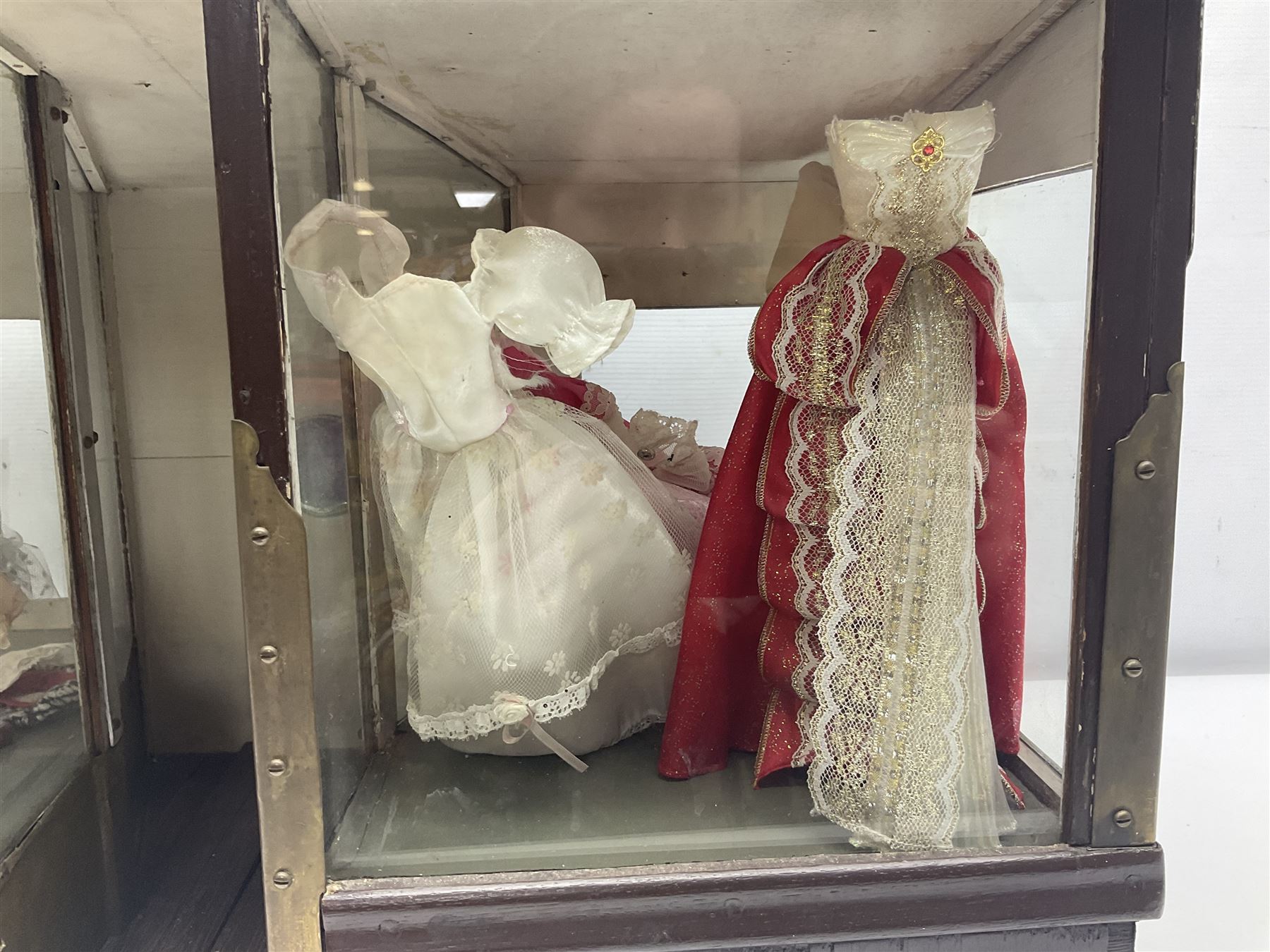 Early 20th century scratch-built wooden hat & gown shop diorama 'Joan', of double-fronted form glazed on three sides with brass and aluminium mounts, rear access apertures and storage under L63cm H45cm D31cm; with small collection of dresses and hats on display stands