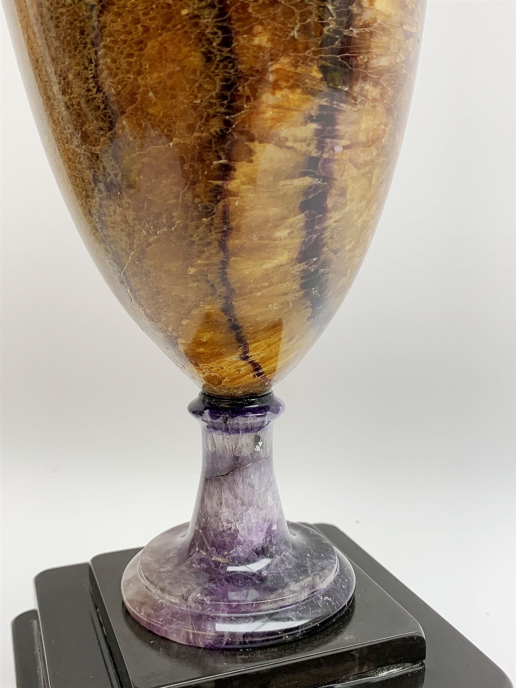 Early 19th century and later Blue John urn, Winnats one vein, of ovoid form with integrated cover and ball finial, upon a spreading circular base, and square stepped black lacquered base, H34.5cm