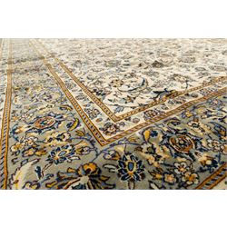 Central Persian Kashan hand-knotted rug, ivory field intricately decorated with an all-over design of scrolling vines, palmettes, and stylized lotus motifs in shades of soft blue, pale gold, and indigo within floral borders