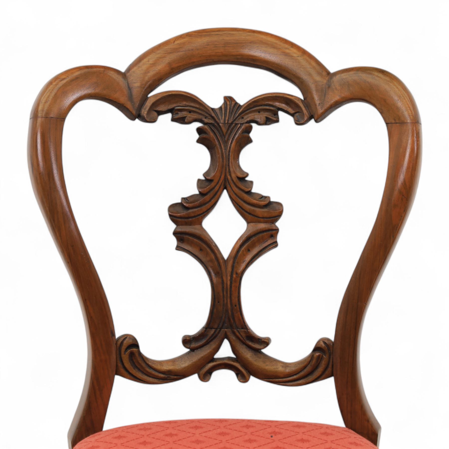 Set of four Victorian walnut balloon back chairs, with a carved and pierced back splat with foliate scrolls, serpentine seat upholstered in a diamond pattern fabric, raised on cabriole legs 