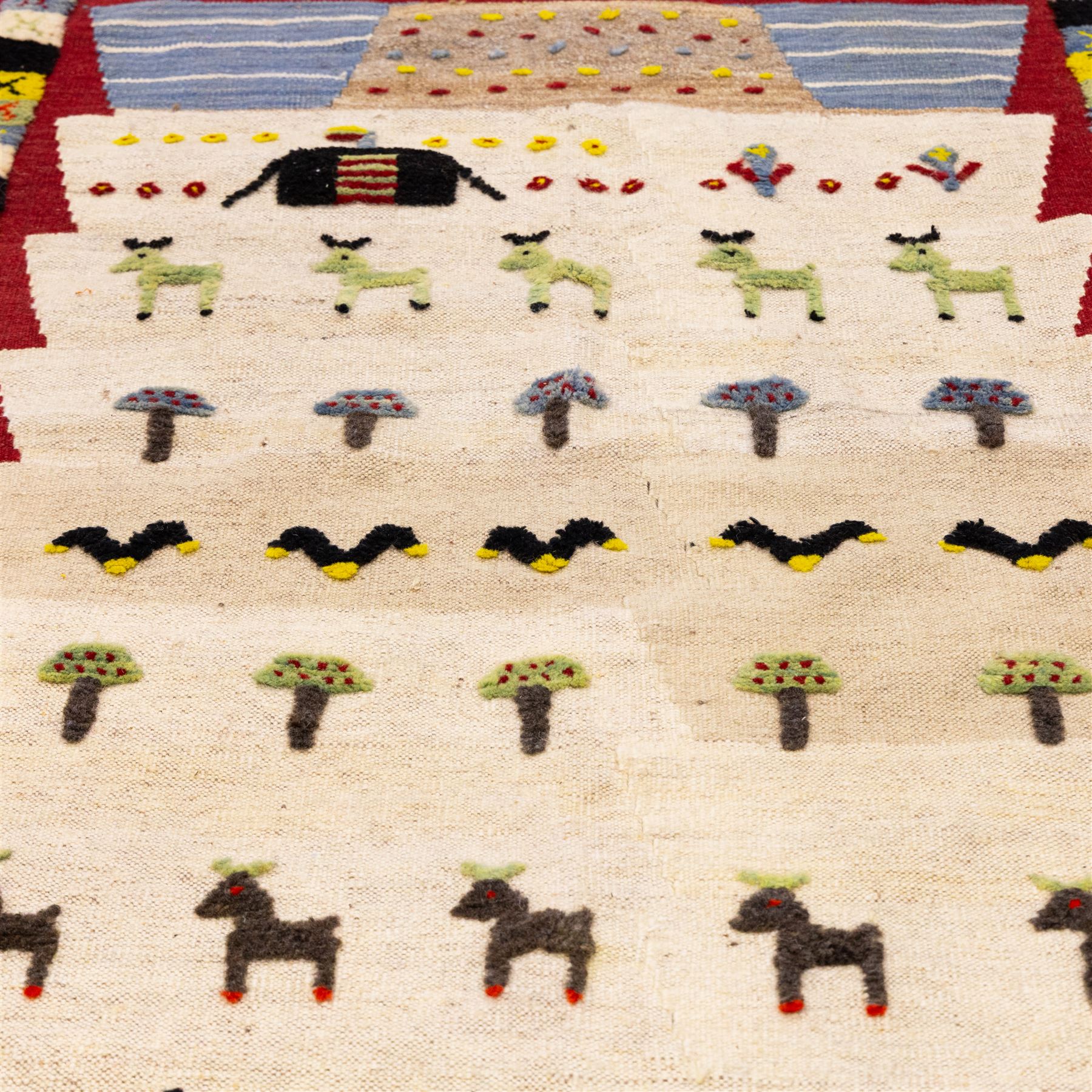 South West Persian Qashqai pictorial flatweave kilim, ivory field decorated with rows of stylized animals, bird and tree motifs applied in raised wool pile against a flat-woven ground, arranged in horizontal bands beneath a simple geometric panel enclosed by a broad red ground border with polychromed geometric devices 
