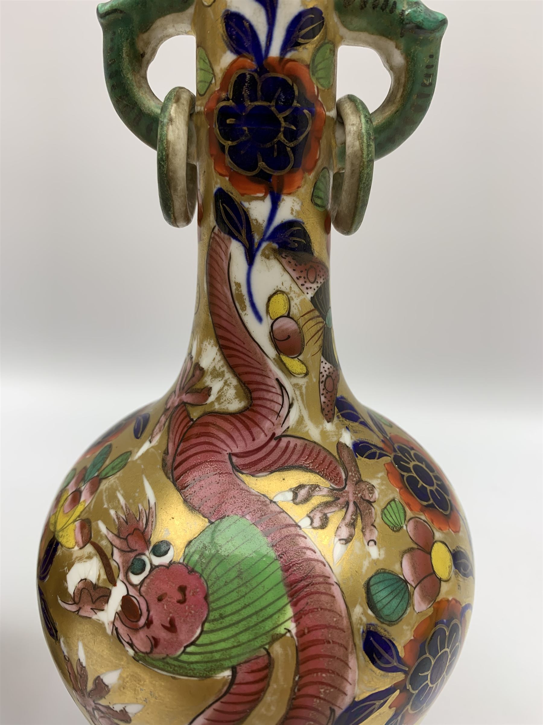 Pair of early 19th century Miles Mason vases, the baluster bodies with tall slender necks supporting twin stylised trunk handles with rings, decorated with Chinese dragons, butterflies, and blossoming flowers against a gilt ground, with spurious Chinese marks beneath in iron red, H27.5cm