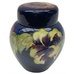 Moorcroft ginger jar, decorated in the Hibiscus pattern upon a blue ground, with paper label beneath detailed 'Potters to the late Queen Mary', H11cm.