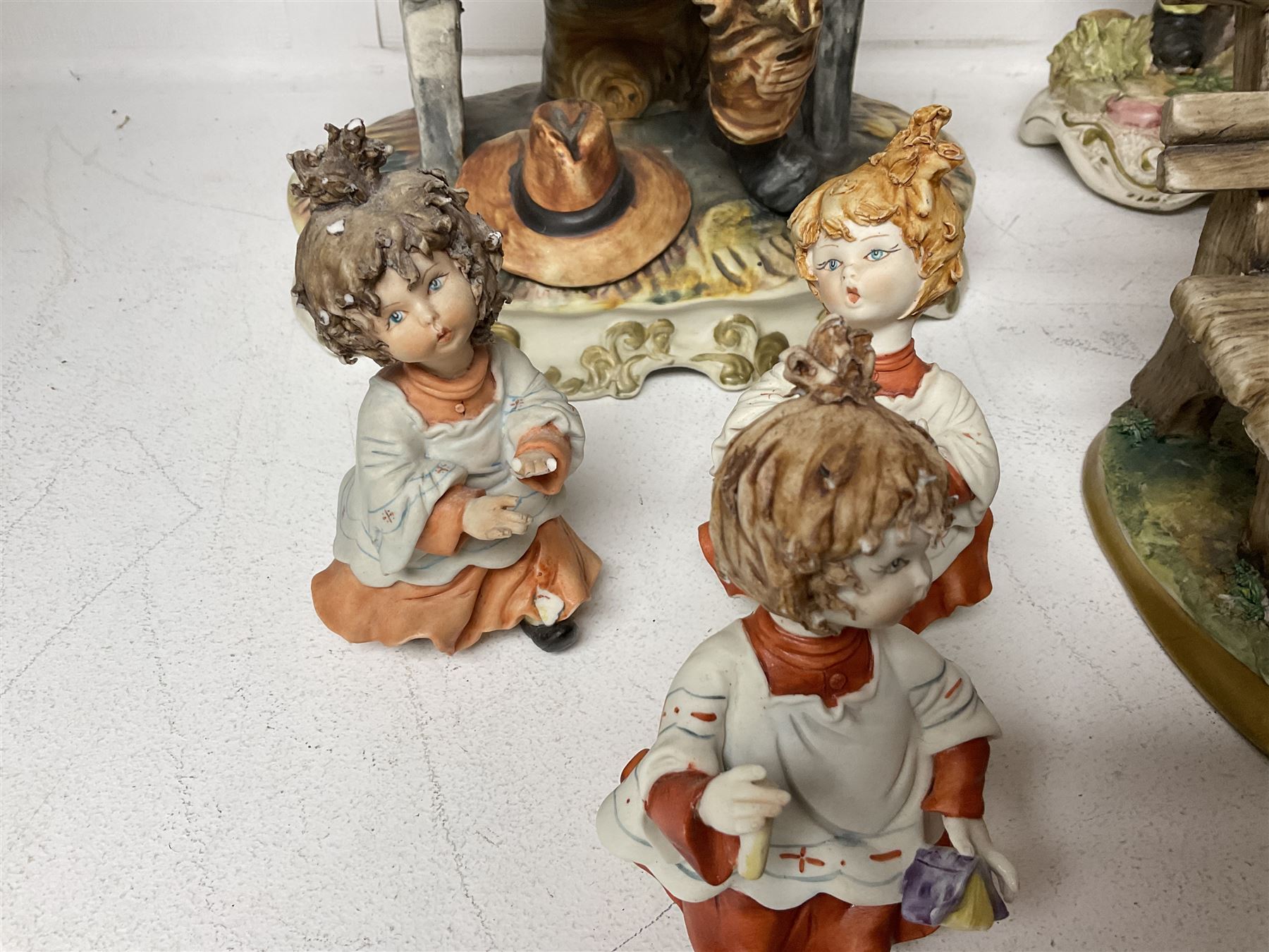 Group of Capodimonte figures, to include musical organ grinder with donkey and monkey, two tramp figures on benches, man with gun and choir boy and girl figures
