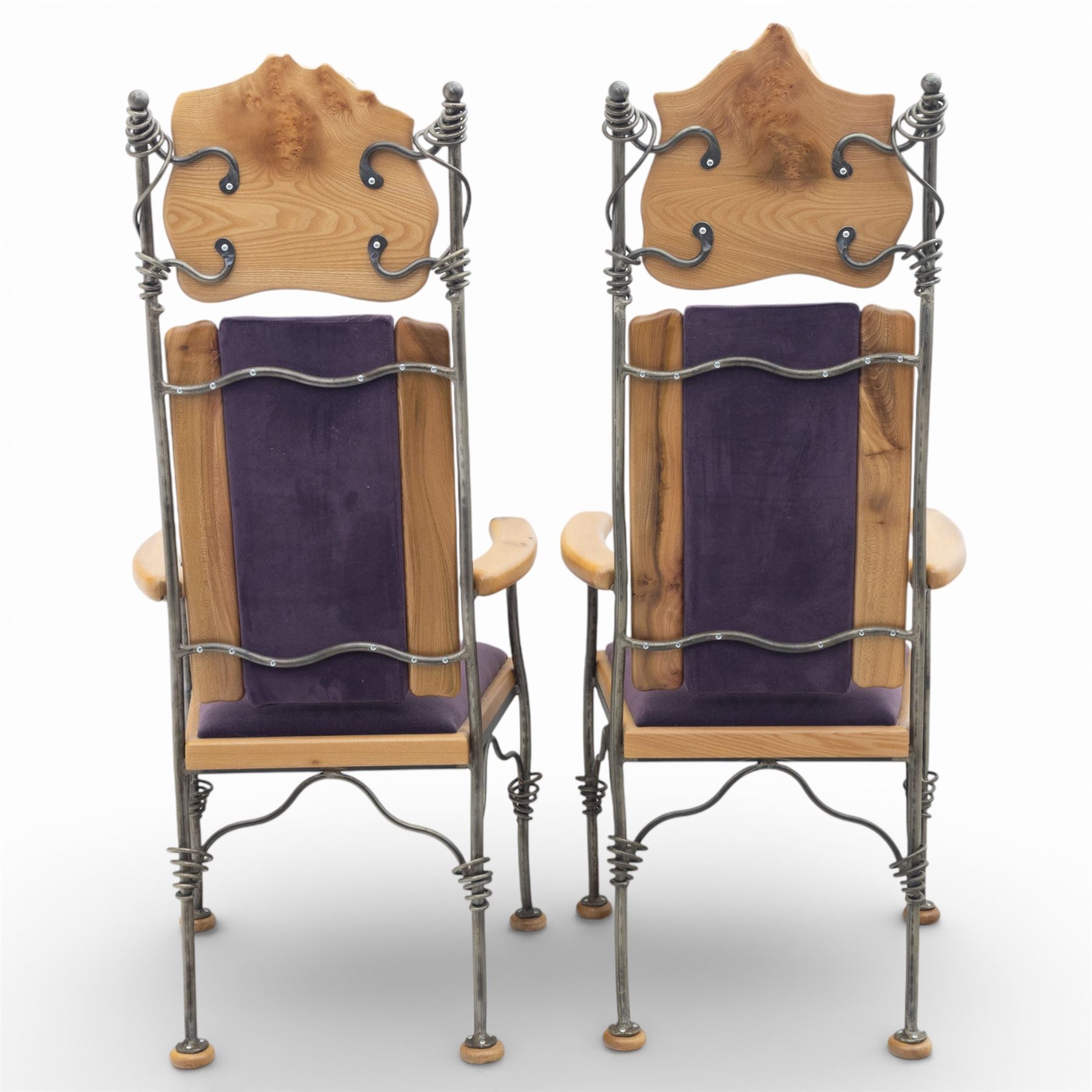 Paul Hodgkiss Designs of Glasgow - contemporary shaped elm dining table with wrought iron base; with set ten (8+2) matching high-back dining chairs, table of organic form above an elaborate wrought iron supports, with central elm stretcher, the chairs with en suite with matching wrought iron work burred elm headrest, purple velour upholstery with drop in seat     

Table: W 102cm, L 243cm, H 74cm
Chairs: W 56cm, D 52cm, H 130cm