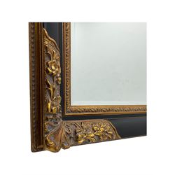 Early 20th century wall-hanging mirror, rectangular bevelled mirror plate within ebonised frame, gilt mounts to the corners carved with floral motifs 