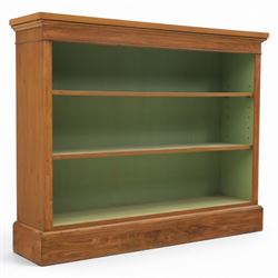 Traditional walnut small bookcase, with projecting cornice above a green painted interior, adjustable shelving, on a moulded plinth base