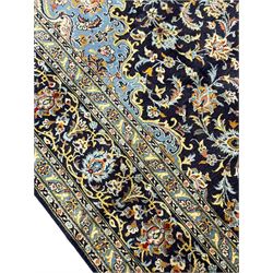 Persian Kashan indigo ground carpet, floral pattern light blue ground central medallion and spandrels, the fielding decorated with interlacing leafy branches and palmettes, the repeating floral pattern border enclosed within guard stripes