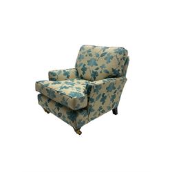 Traditional shaped armchair, upholstered in blue and cream floral fabric, on tapered supports with castors 