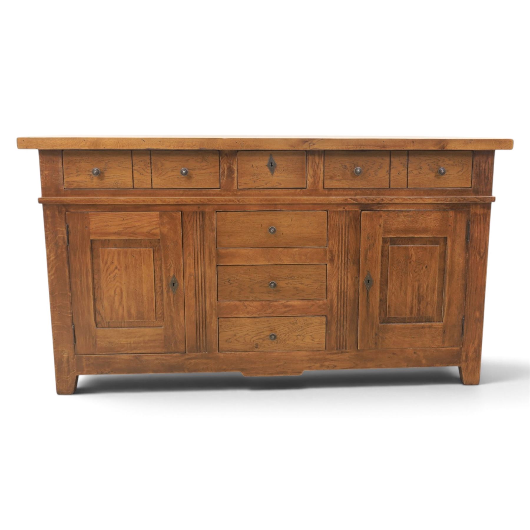 Indigo Furniture - large rustic oak sideboard fitted, with three drawers above three central drawers, flanked by fielded panelled doors, raised on bracket feet