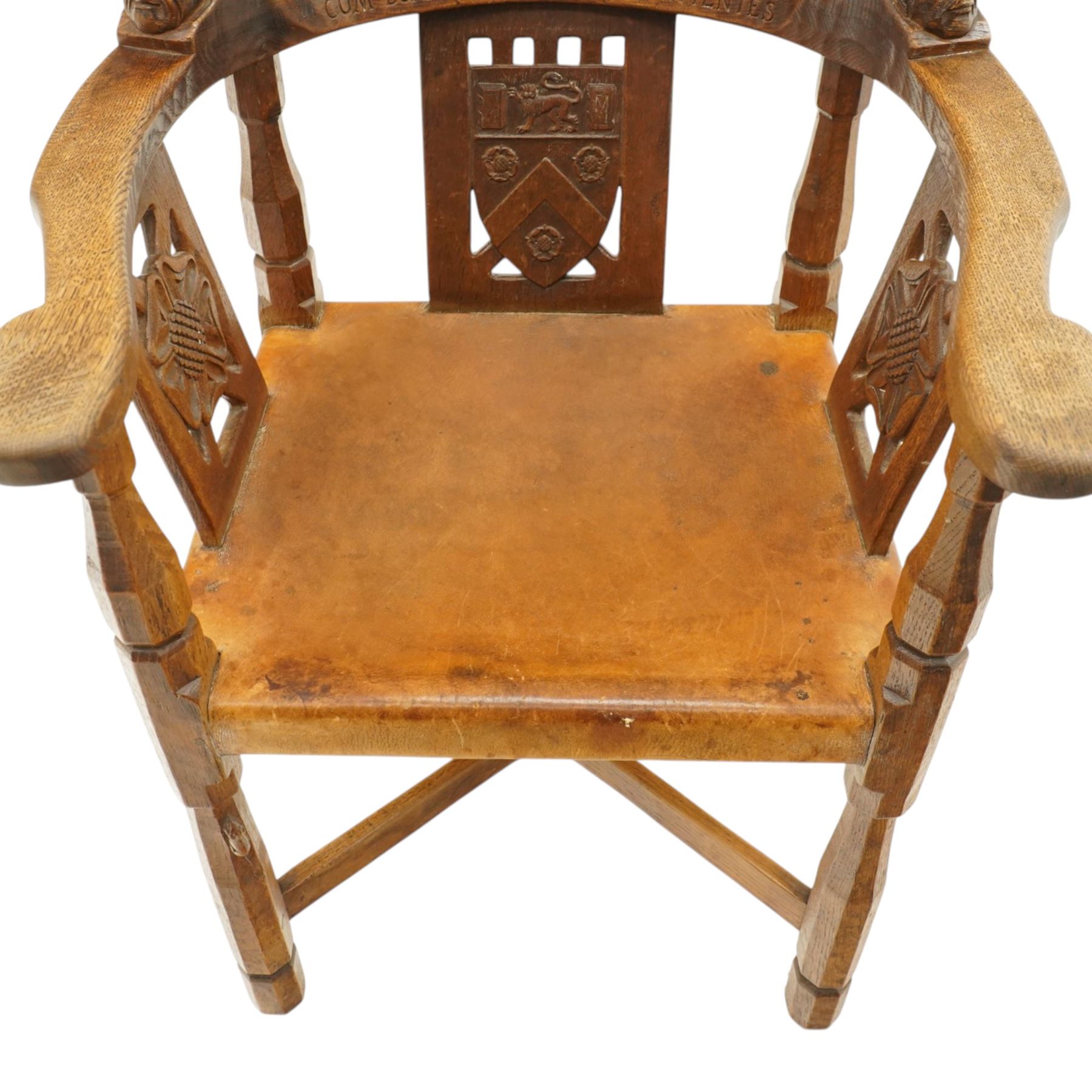 Mouseman - important oak monks chair, c1930s, the curved back inscribed with motto 'Cum Bona Voluntate Servientes' (serving with goodwill) over Trinity College Cambridge coat of arms, the shaped arms terminating with carved monks heads, each pierced side panel with Yorkshire Rose, tan leather seat on four octagonal legs joined by a cross stretcher, the back of the chair with initials ECH, with carved mouse signature, by Robert Thompson of Kilburn