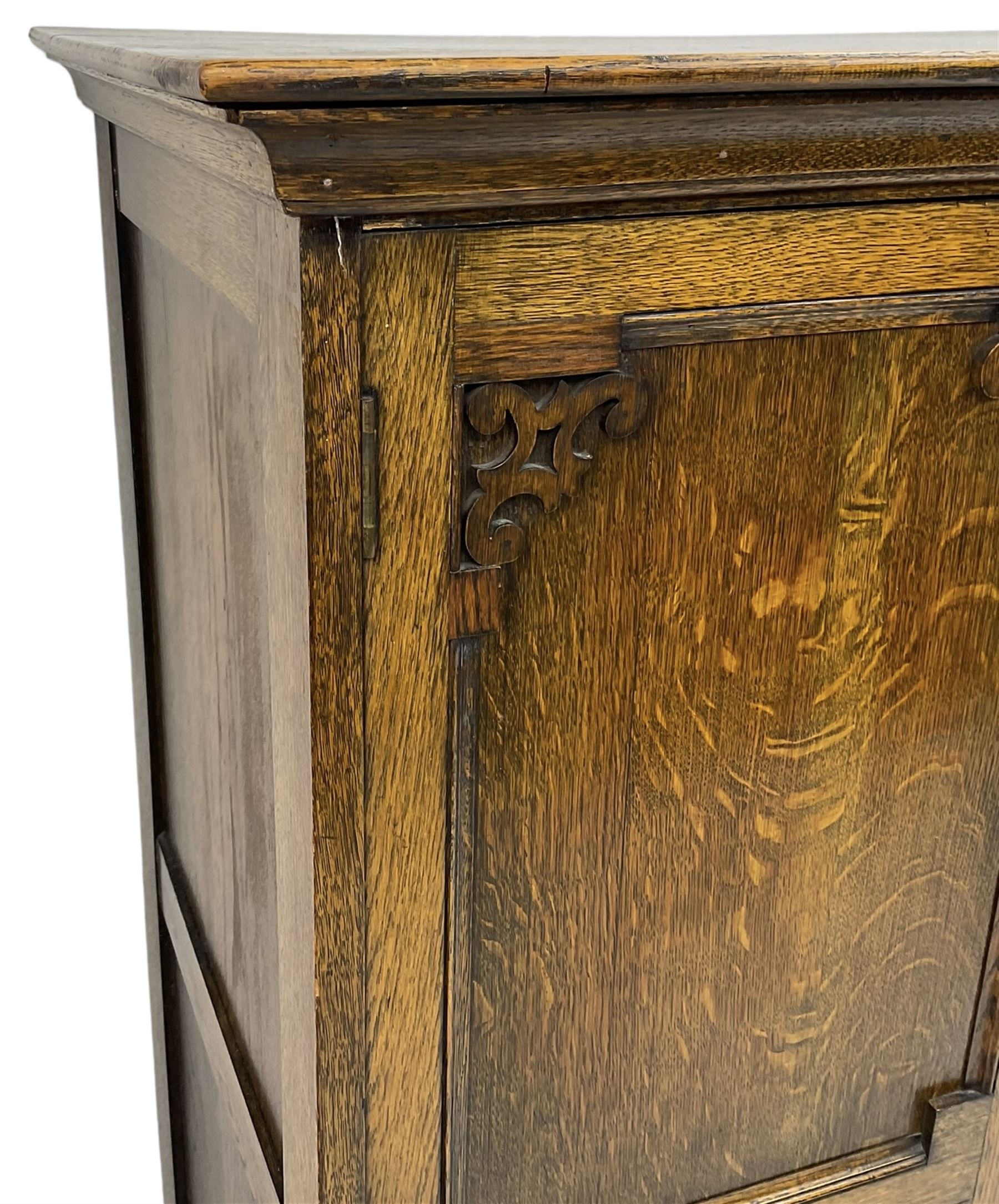Early 20th century oak triple wardrobe, three panelled doors with geometric mouldings and fretwork spandrels, the interior fitted with slides and hanging rail