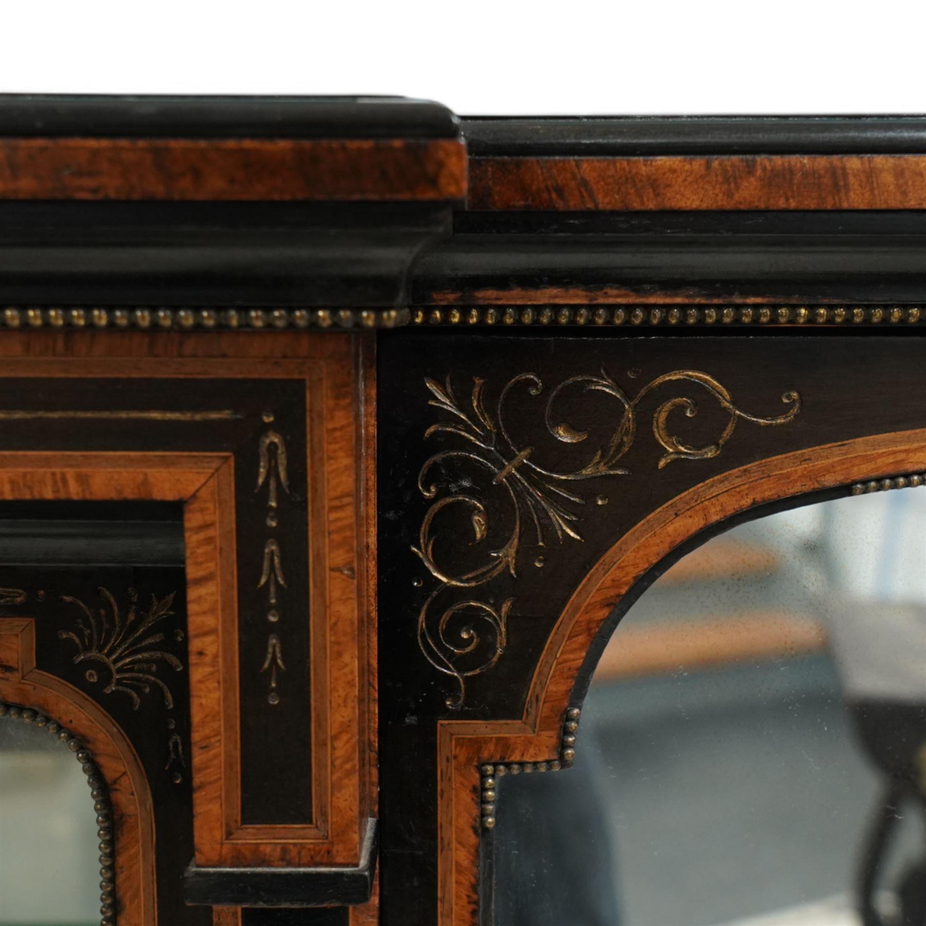 Victorian amboyna and ebonised credenza with glass top, the freeze fitted with two Wedgewood plaques and brass beading above crossbanded arched glazed mirror door flanked by two glazed cabinet doors with two removable glass shelves between four gilt brass reeded floral columns, supported on bun style feet