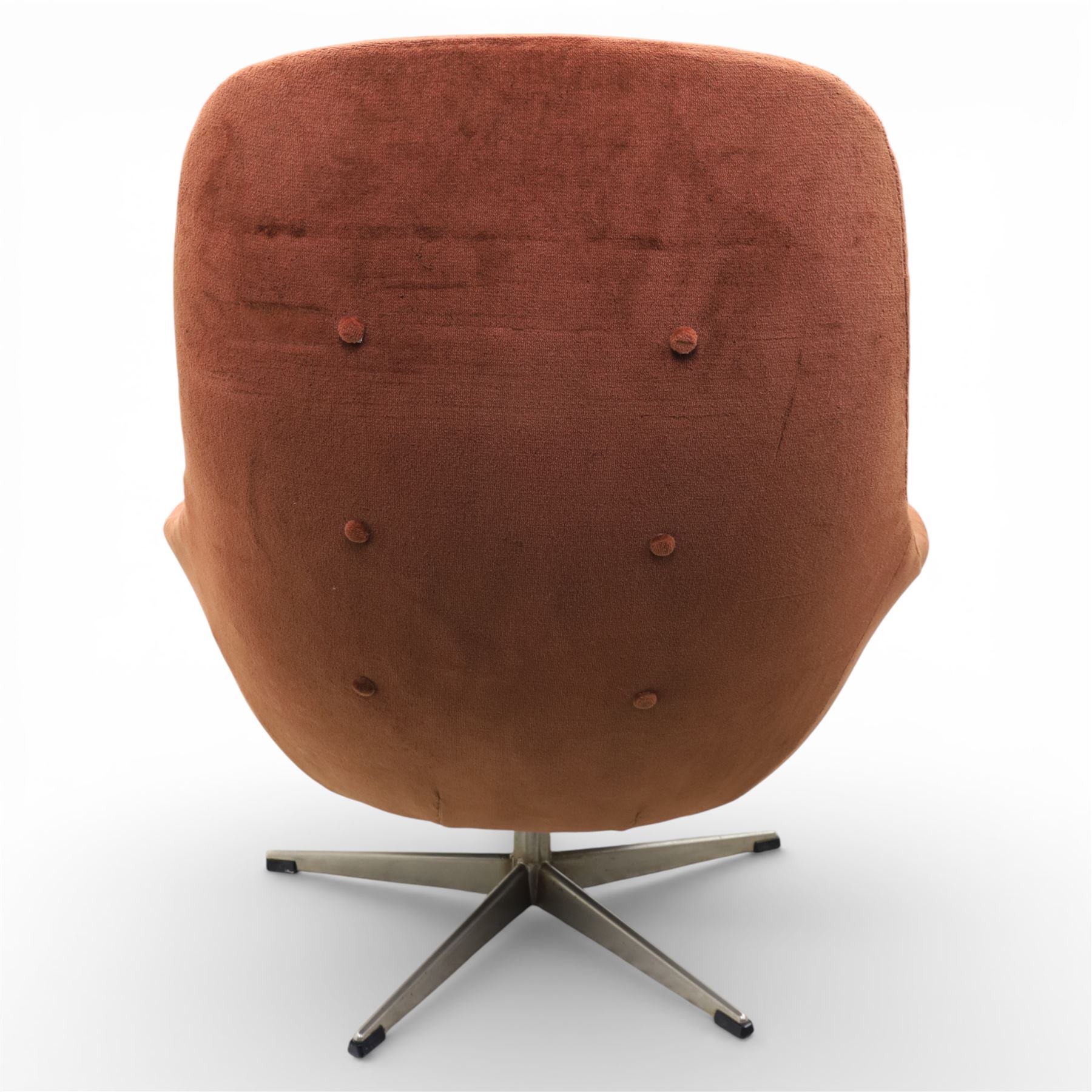 Pair of mid 20th century brown velvet swivel lounge chairs and matching footstool, the shaped and padded back with buttoned segmented cushion over conforming seat cushion, flared armrests and moulded sides, raised on a five point metal swivel base, the footstool en suite with buttoned cushion and matching metal base