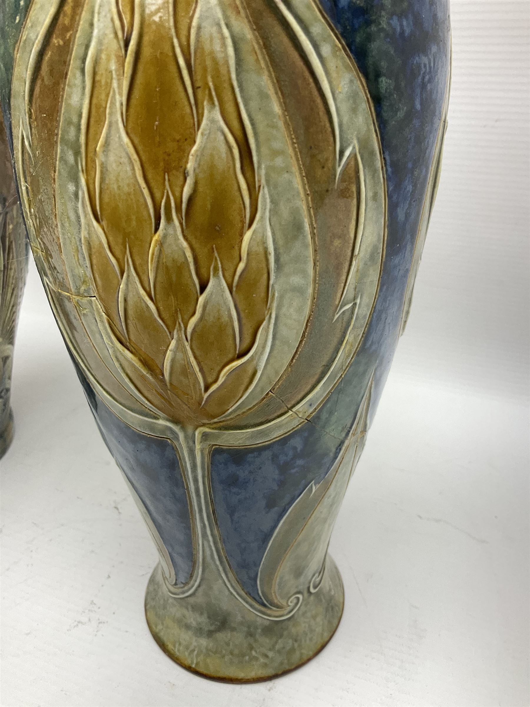 Early 20th century Royal Doulton stoneware vase, decorated with a stylized floral design below a wavy rim, monogrammed B.N, possibly for Bessie Newbery, H28cm, together with an early 20th century glazed jug, heavily carved throughout (2)