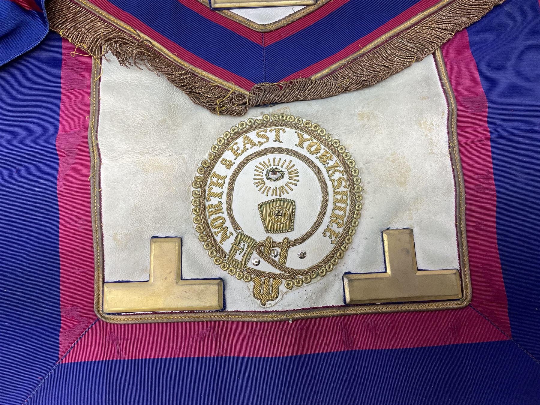 Two Masonic kid leather aprons, one with sash and cuffs, the other with sash, each marked 'Yorkshire North and East Ridings'; and three other unmarked Masonic aprons with sashes