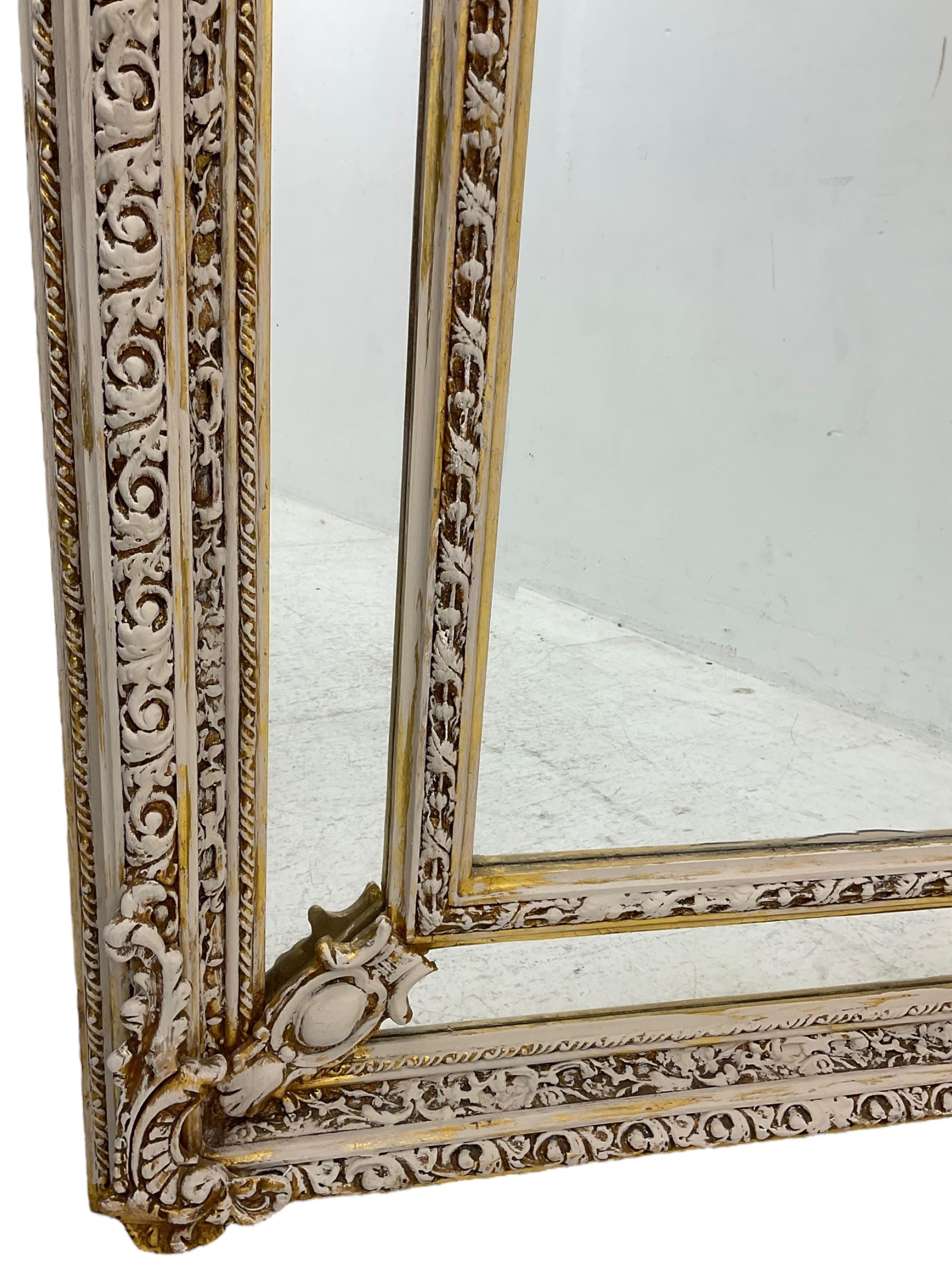 Large painted and gilt arched wall mirror, the frame decorated with scrolling leafy branches, central bevelled mirror mirror surrounded by plain panels, decorated with cartouche mounts 
