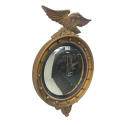 Regency design gilt famed wall mirror, eagle pediment on a rocky plateau, the circular convex plate within a reeded ebonised slip, frame decorated  with applied spheres