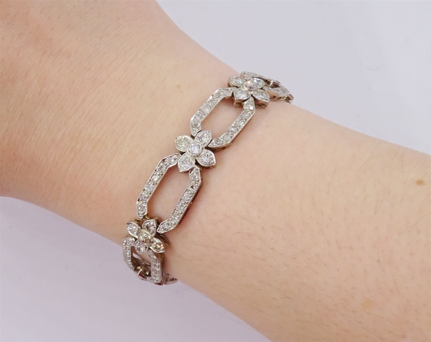 18ct white gold and platinum, milgrain set old cut diamond flower head and openwork panel link bracelet, total diamond weight approx 4.25 carat
