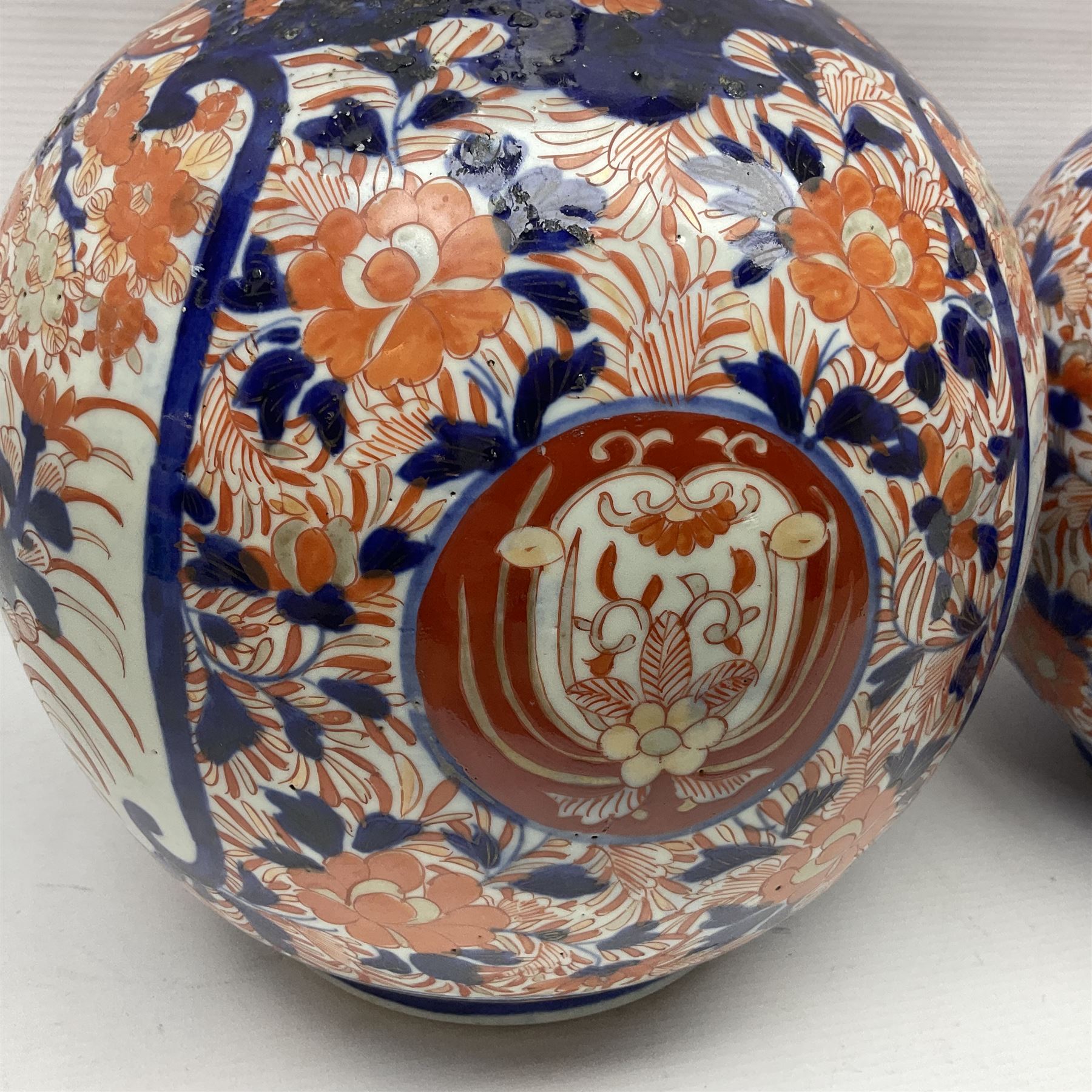 Pair of large 19th century Japanese Imari porcelain bottle vases, painted with shaped reserves of peonies, chrysanthemums and prunus blossom, each H46cm